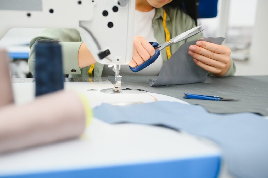 Young woman working as seamstress in clothing factory.